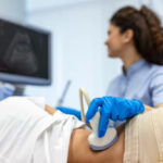 Doctor conducts ultrasound examination of patientv kidneys. Internal organs ultrasound concept. female's lower back diagnosis carried out with the use of an ultrasound