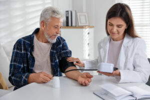 A doctor measures a patient's blood pressure at a table in the hospital during treatment for hypertension management.